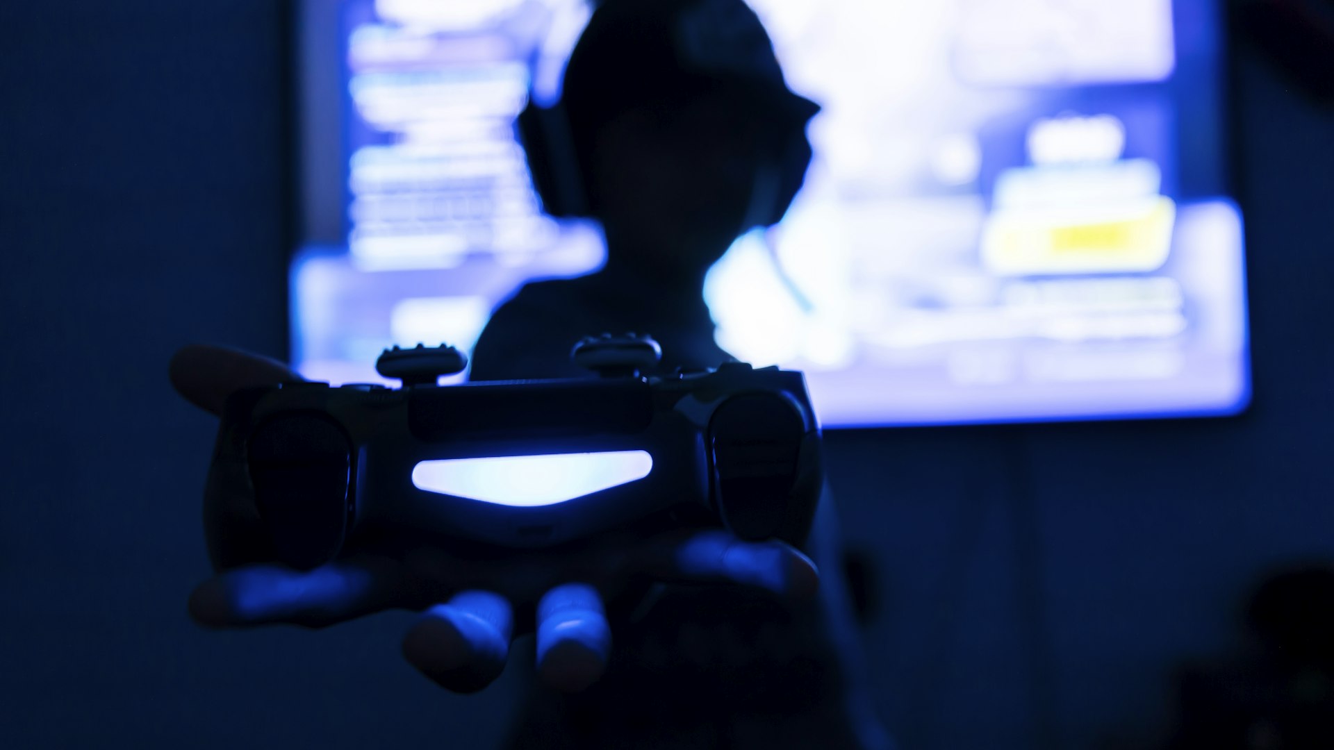 A dimly lit gaming desk with mechanical keyboard and controller